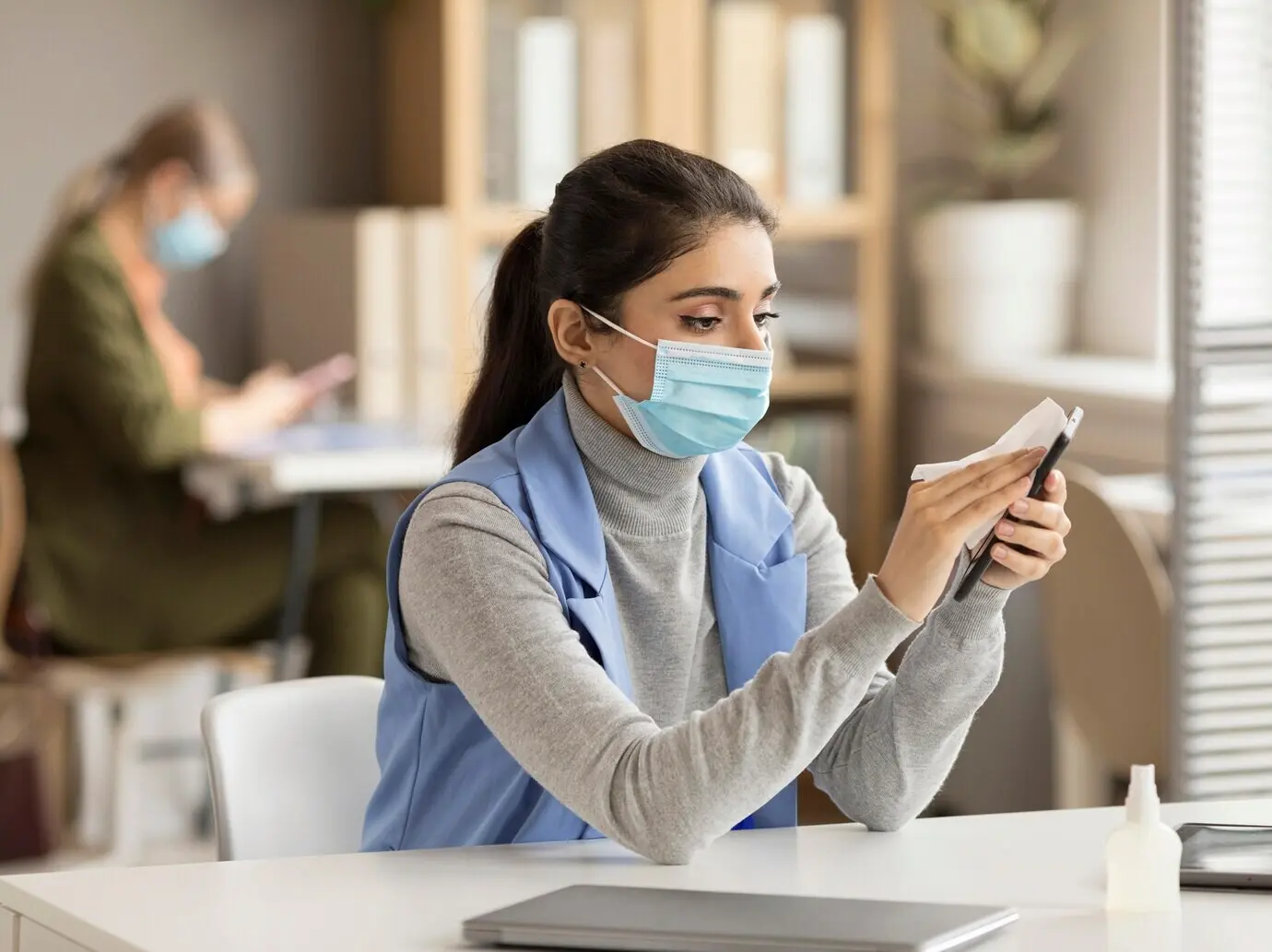 Сотрудник дезинфицирует электронное устройство.