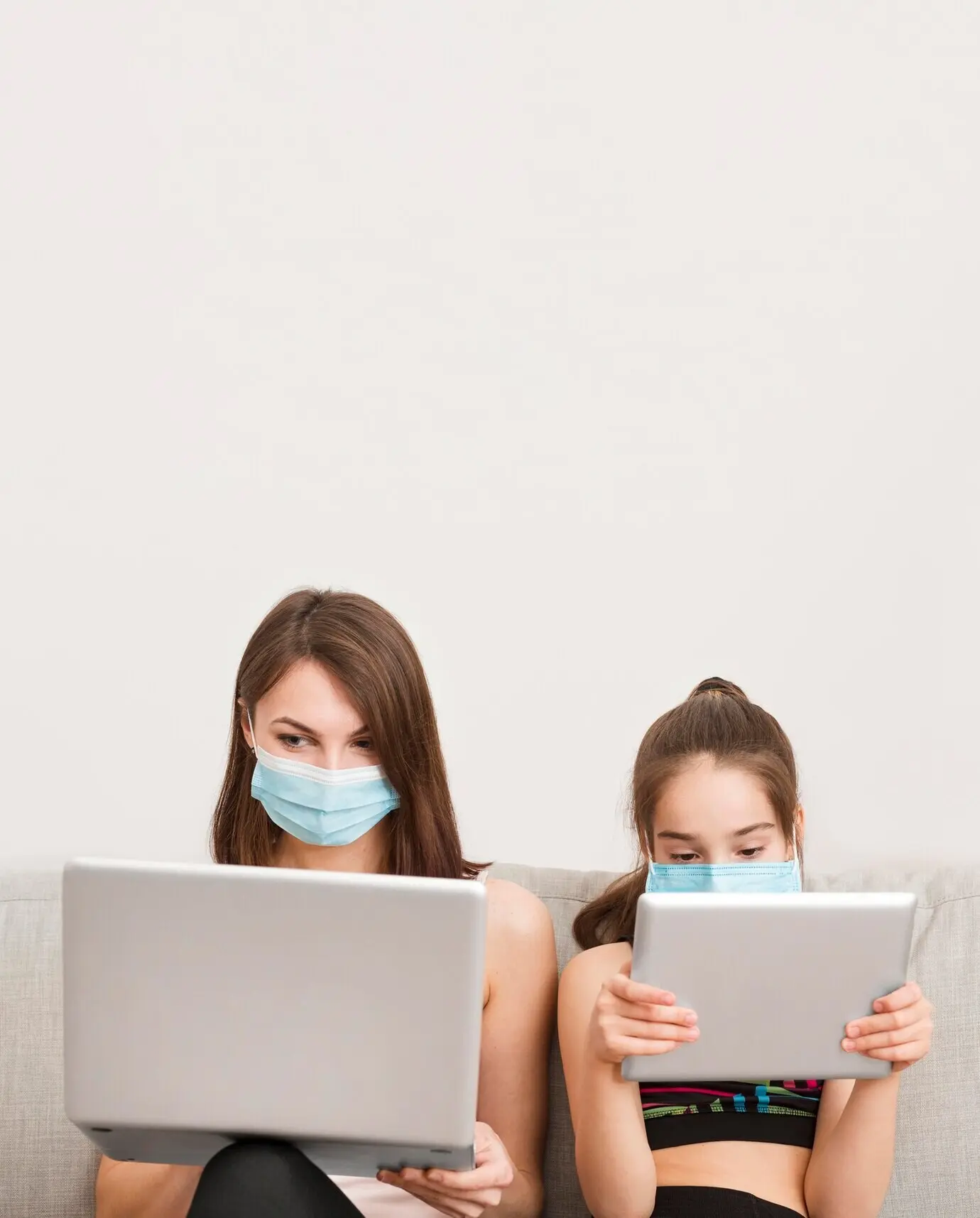 Девочка и мама на диване с электронным устройством.